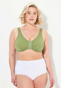 Grüner nahtloser BH mit runden Cups und breiten Trägern, der eine Frontverschlus hat. Kombiniert mit hochgeschnittenen weißen Slips mit einem kleinen Schleifchen.