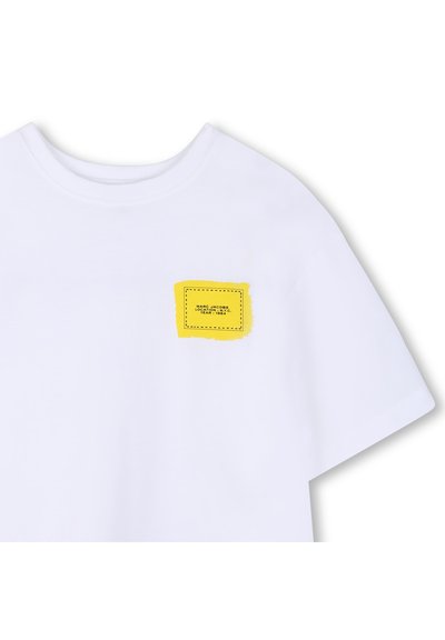 Wit T-shirt van katoen, met een gele rechthoekige patch met zwarte stiksels en tekst op het linkerborstgebied.