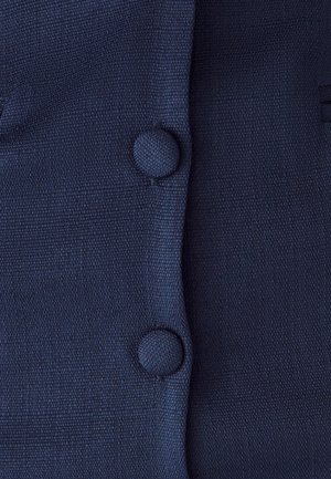 Tmavě modrá texturovaná tkanina se dvěma kulatými knoflíky vpředu. Materiál se zdá být tkaný s jemným, žebrovaným vzorem.
