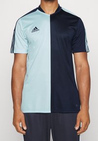 Jersey de manga corta dividido verticalmente en azul claro y azul marino oscuro, con el logo de Adidas, cuello y tres rayas en los hombros.