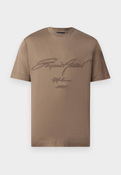 T-shirt de algodão castanho com mangas curtas, apresentando texto bordado em castanho escuro. Design simples de gola redonda com um ajuste descontraído.