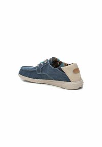 Zapato casual de denim azul con acentos beige, cierre de cordones y suela texturizada. El interior cuenta con un forro con patrón. Forma de punta redondeada.