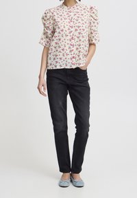 Květinová halenka v krémové barvě s růžovými vzory, krátké nabírané rukávy, zapínání na knoflíky; v kombinaci s přiléhavými černými džíny a modrými balerínami.