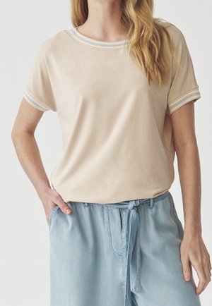 T-shirt beige à manches courtes avec un col rond, présentant une bordure rayée bleu clair et blanche le long du col et des manches.