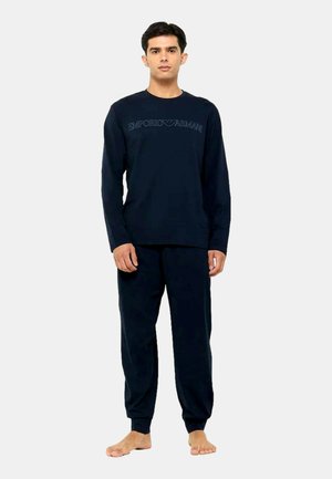 Navy blue loungewear set featuring long-sleeve shirt and matching pants. Shirt has "Emporio Armani" logo across the chest. Soft fabric, relaxed fit.