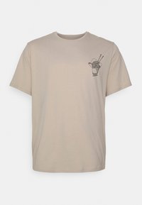 T-shirt en coton beige à manches courtes, avec un graphisme noir représentant un contenant à emporter et des baguettes sur la partie gauche de la poitrine.