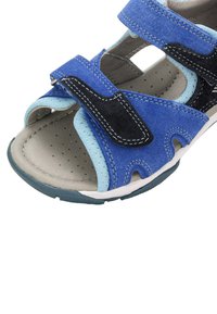 Niebieskie i czarne sandały z miękką zamszową cholewką, regulowanymi paskami na rzep, otwartym noskiem, perforowaną wkładką i teksturowaną gumową podeszwą.