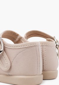 Beige Leinenschuhe mit strukturiertem Finish, abgerundeter Rückseite, Riemen mit einer silbernen Schnalle und einer weichen Gummisohle.