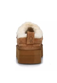 Scarpe platform in camoscio marrone con una soffice fodera bianca, caratterizzate da un design cucito e un tallone con linguetta per facilitarne la calzata.