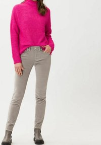 Pull en tricot fuchsia à col montant, associé à un pantalon en velours côtelé gris clair et des bottines noires. Design simple et coupe décontractée.