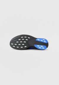 Semelle de chaussure de sport noire avec des accents bleus, dotée d'une surface texturée et de grips blancs à motifs pour l'adhérence. Marque Continental visible.