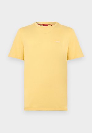 Gelbes T-Shirt mit kurzen Ärmeln und Rundhalsausschnitt, mit kleinem weißen "HUGO"-Logo auf der linken Brust, dargestellt auf einem einfarbigen hellgrauen Hintergrund.