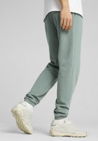 Joggers verde menta fabricados con una tela suave, con una cinturilla y puños elásticos, combinados con zapatillas texturizadas en color blanco roto.