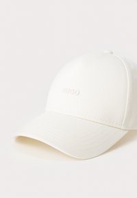 Weißer Baseballcap aus Baumwolle mit gebogenem Schirm und geprägtem "HUGO"-Logo auf der Vorderseite. Strukturiertes Material mit gestickten Akzenten.