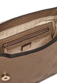 Interno di una borsa a tracolla in pelle marrone con texture, dotato di una tasca con zip e logo del marchio sulla fodera in tessuto. Presenta un design impresso e hardware dorato.