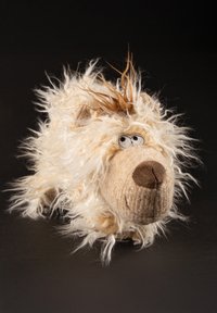 Plüschhund mit zotteligem weißen Fell, brauner Schnauze und kleinen schwarzen Augen. Besitzt einen strukturierten Körper mit verstreuten längeren Fasern für einen verspielten Look.