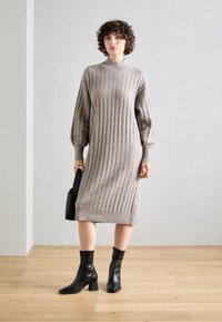 Neulos gray ribbed dress with a high neckline and puffed sleeves, paired with black ankle boots and a small black handbag.