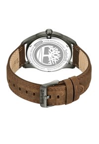 Orologio con cinturino in pelle marrone e cassa in acciaio inossidabile, con fondo trasparente che mostra un logo e resistenza all'acqua fino a 5 ATM.