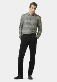 Grau gestreiftes Langarm-Poloshirt mit Kragen, kombiniert mit schwarzen Cordhosen und schwarzen Stiefeln, mit einer figurbetonten Silhouette.