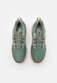 Para zielonych i koralowych butów biegowych Asics widzianych z góry na białym tle.