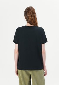Black cotton t-shirt with a relaxed fit, rounded neckline, short sleeves, and a smooth texture. No visible logos or patterns.