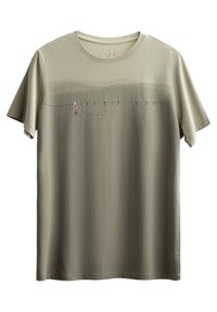 Maglietta verde oliva a maniche corte, caratterizzata da un sottile design a gradiente e un'illustrazione stampata di una figura che cammina accanto a una recinzione.