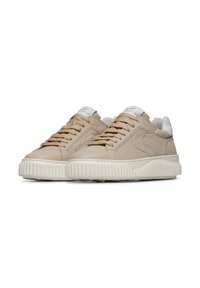 Sneaker in pelle beige con finitura testurizzata, accenti bianchi, punta rotonda e suola in gomma spessa e rigata. Lacci dello stesso colore beige.