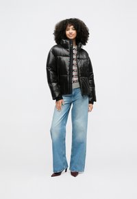 Μαύρο γούνινο μπουφάν με ψηλό γιακά, γυαλιστερό φινίρισμα και φερμουάρ μπροστά. Συνδυασμένο με άνετο μπλε τζιν και μπορντό γόβες με τακούνι.