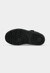 Mustad spordijalatsite tald ringikujuliste tallamustrite ja väikese Nike logoga keskel, kuvatud ühevärvilise heleda tausta ees.