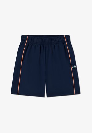 Marineblå treningsshorts med elastisk midjebånd, har oransje sidekant og grønn krokodillelogo på venstre kant. Myk stofftekstur.