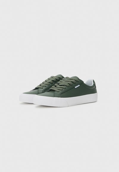 Green synthetic sneakers with a smooth texture, featuring flat laces, white rubber soles, and a minimalistic design accent.