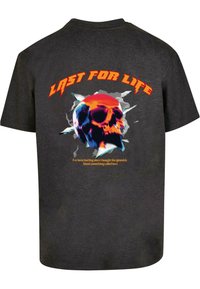 Černé bavlněné tričko s barevným potiskem lebky, výrazným textem "LAST FOR LIFE" a doplňujícím textem v oranžové barvě. Krátké rukávy, kulatý výstřih.