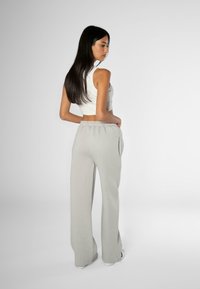 Light gray sweatpants with a relaxed fit, elastic waistband, and side pockets, paired with a cropped white tank top.