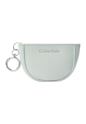 Lichtblauwe Calvin Klein halfmaanvormige pouch met stikseldetails en een zilveren sleutelhanger eraan bevestigd, op een witte achtergrond.