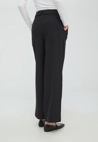 Pantaloni neri a gamba larga con una texture liscia, presentano una vita sagomata, tasche laterali e un design anteriore piatto.