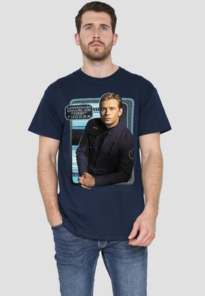 Dunkelblaues T-Shirt mit einem Grafik eines Charakters in einer Sci-Fi-Uniform, mit Textüberlagerung "Kommandant Charles 'Trip' Tucker."