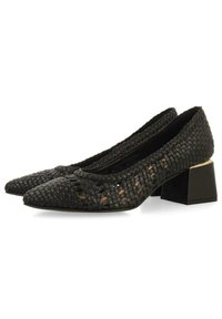 Zapatos de tacón de cuero trenzado negro con punta afilada y tacón bloque, presentando una base negra suave y un discreto detalle de recortes.