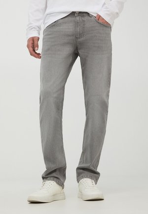Jeans in denim grigio con taglio dritto. Presentano passanti per cintura, tasche anteriori e posteriori e una consistenza liscia. Indossati con sneakers bianche.