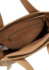 Innenraum einer handgefertigten Handtasche aus tanfarbigem Leder, ausgestattet mit einer Reißverschluss-Tasche und einem glatten Stofffutter. Zusätzlich gibt es eine offene Tasche und strukturierte Seiten.