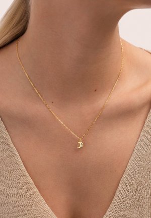 Collar de oro con una cadena delicada y un colgante en forma de luna creciente. La superficie es lisa, reflejando la luz, sobre un fondo neutro.