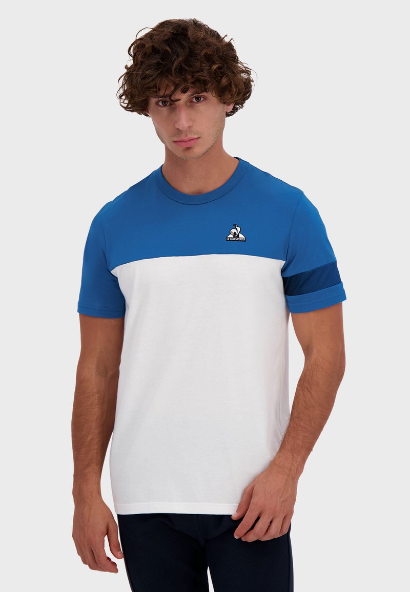 Camiseta de cuello redondo para hombre con una sección superior azul y una sección inferior blanca. Presenta mangas cortas y un pequeño logo en el pecho. Mezcla de algodón.