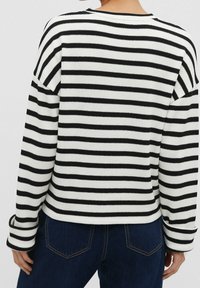 Pull rayé noir et blanc avec une texture côtelée, col rond et coupe décontractée. Caractéristiques : manches longues et ourlet droit.