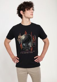 Czarny t-shirt z grafiką robota czaszki z niebieskimi oczami oraz czerwonymi i szarymi wzorami obwodów. Krótkie rękawy i okrągły dekolt.