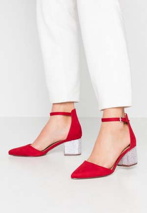 Chaussures à talons hauts en velours rouge, avec des pointes fines, une bride à la cheville et des talons en bloc argentés scintillants. Texture lisse avec une finition synthétique.