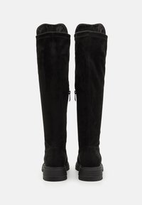 Knee-high black suede boots with a smooth texture, featuring a chunky rubber sole and zipper closures on the inner sides.