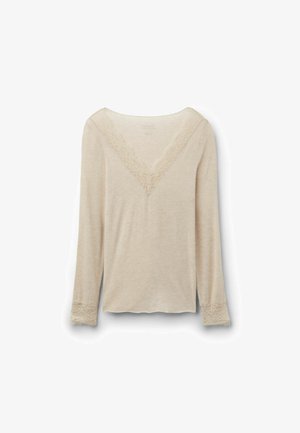 Top beige de manga larga con escote en V y ribete de encaje en el escote y los puños, mostrado sobre un fondo blanco liso.