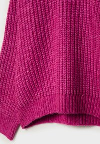 Gros plan sur la moitié inférieure d’un épais pull en tricot côtelé fuchsia montrant la texture détaillée du tricot.
