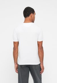 Witte t-shirt met korte mouwen en een ronde hals, gemaakt van zachte stof. Heeft een eenvoudig ontwerp zonder zichtbare patronen of logo's op de achterkant.