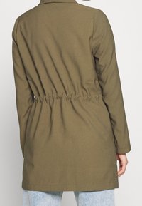 Olive green coat with a cinched waist, long sleeves, flat collar, and smooth fabric texture. Simple design with no visible patterns or accents.