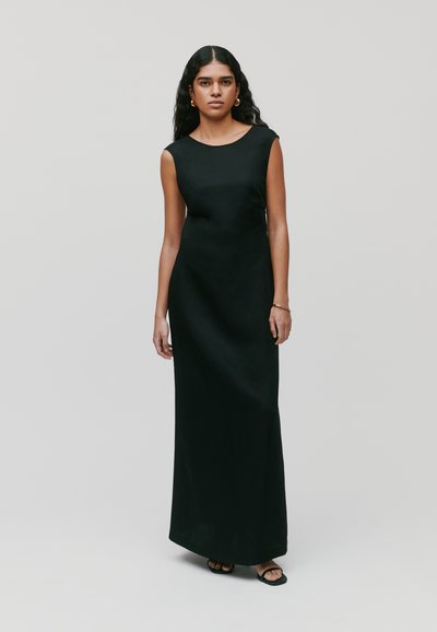 Vestido maxi negro sin mangas, diseño elegante, textura suave, silueta recta, escote redondo, combinado con sencillas sandalias negras.